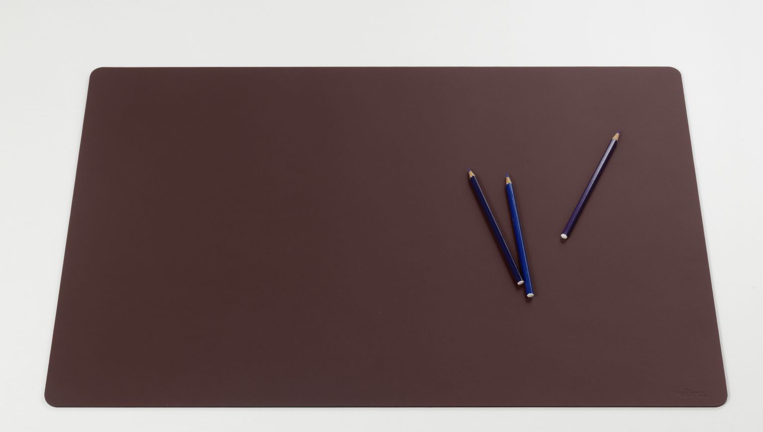 Dunkelrote Repad Schreibtischunterlage von Vitra mit drei Buntstiften auf weißem Hintergrund. Büroaccessoire für den Schreibtisch.