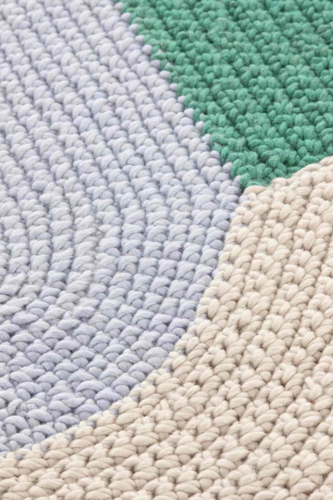 Detailaufnahme des The Crochet Collection Teppichs in Blau, Grün und Beige, handgefertigter Wollteppich.