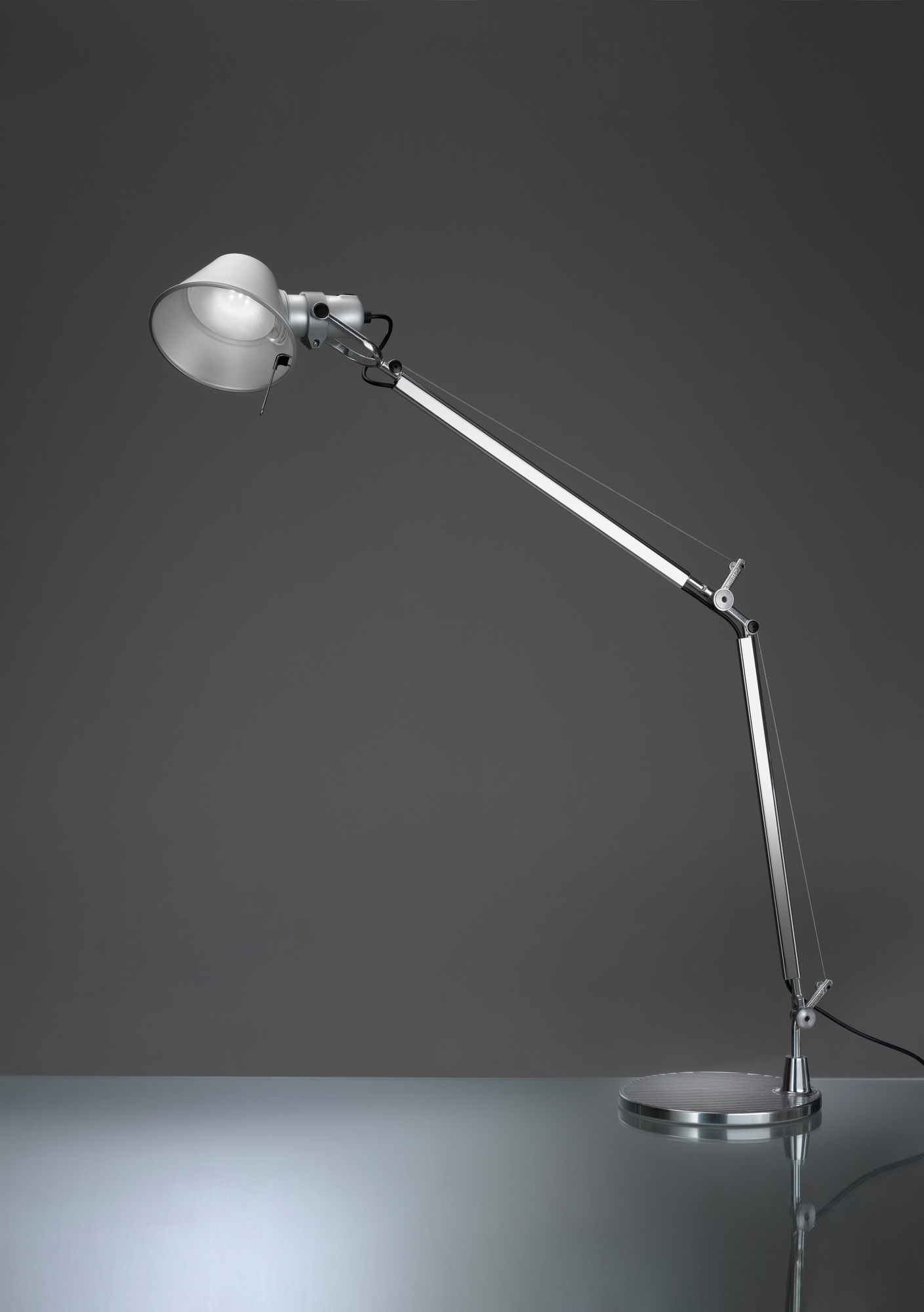Artemide Tolomeo Tischleuchte mit weißem Lampenschirm und silbernem, verstellbarem Arm auf rundem Tischfuß.