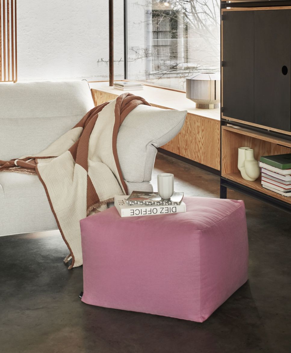 Wohnzimmer-Szene mit Bonbon Shade Lampe (nicht im Bild), rosa Hocker und moderner Einrichtung.
