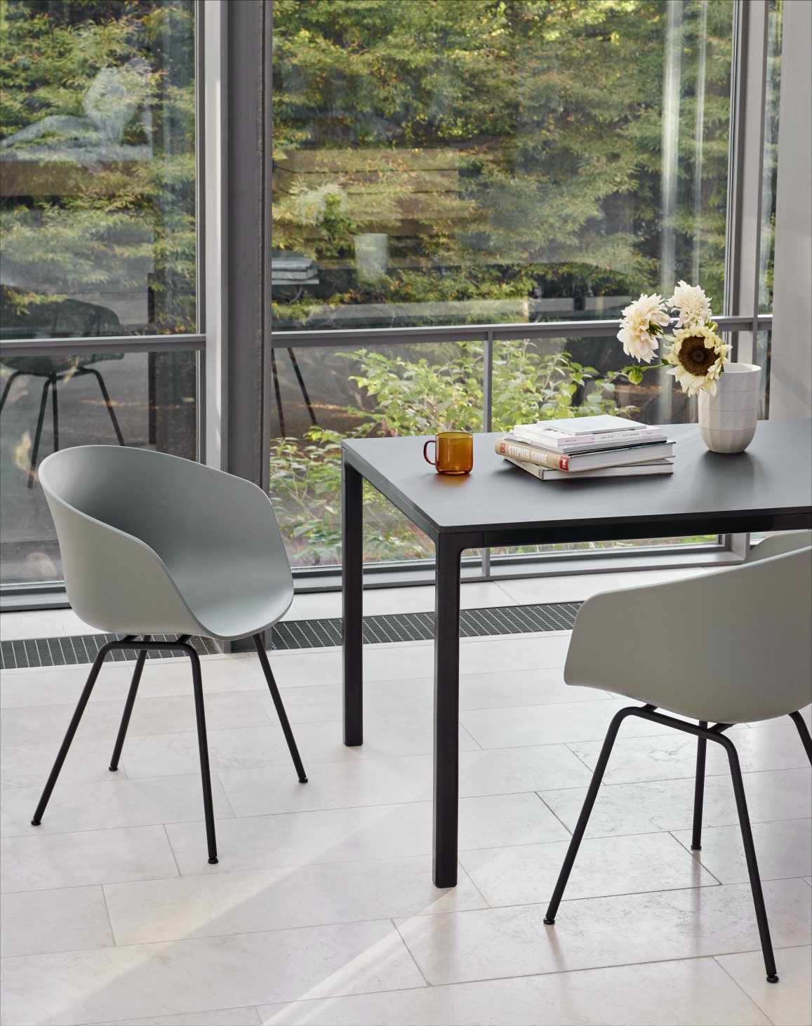 About A Chair AAC26 Stuhl in Dusty Mint mit schwarzem Tisch und Dekoration.