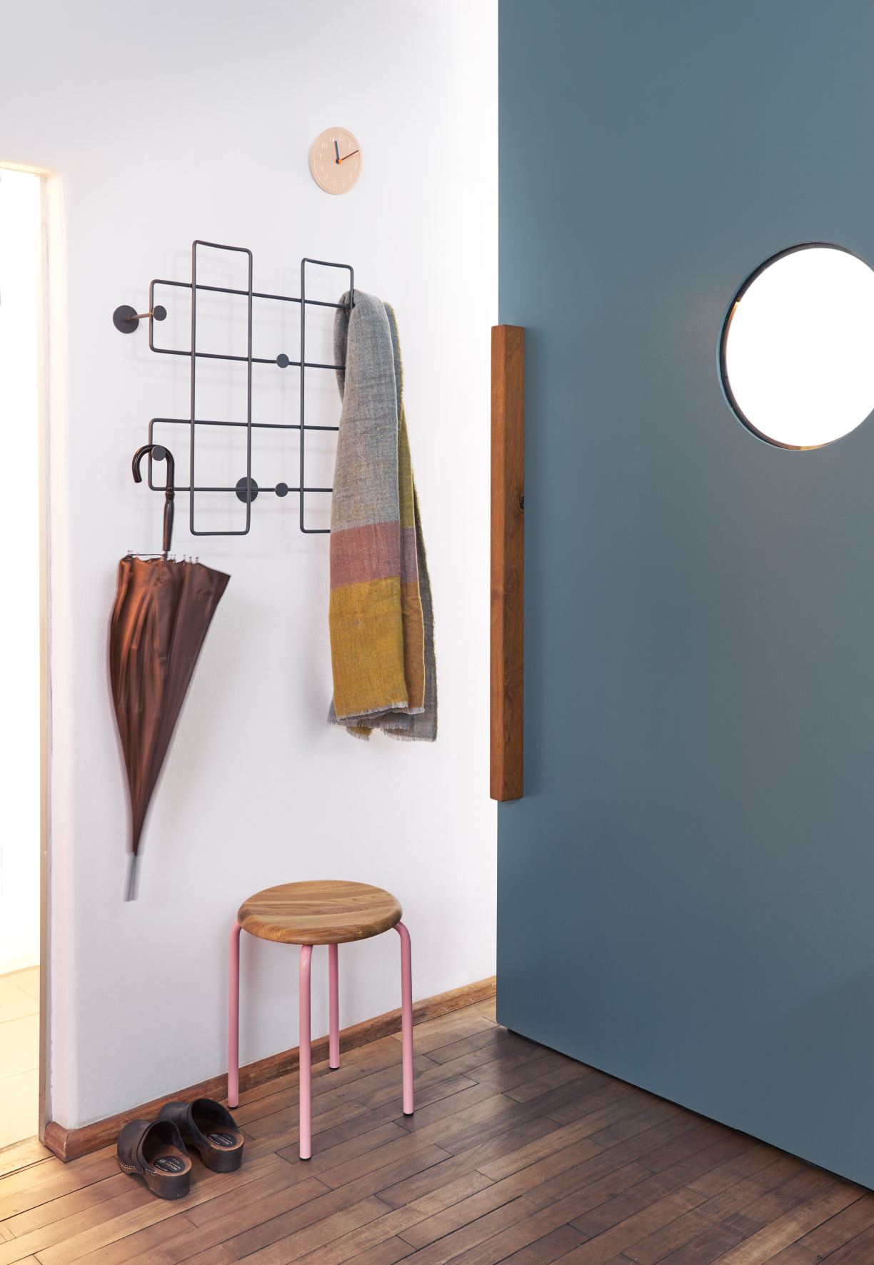 Eingangsbereich mit Richard Lampert Stapelhocker, Holz-Sitzfläche, rosa Beinen, Garderobe, Schirm und Holzboden.