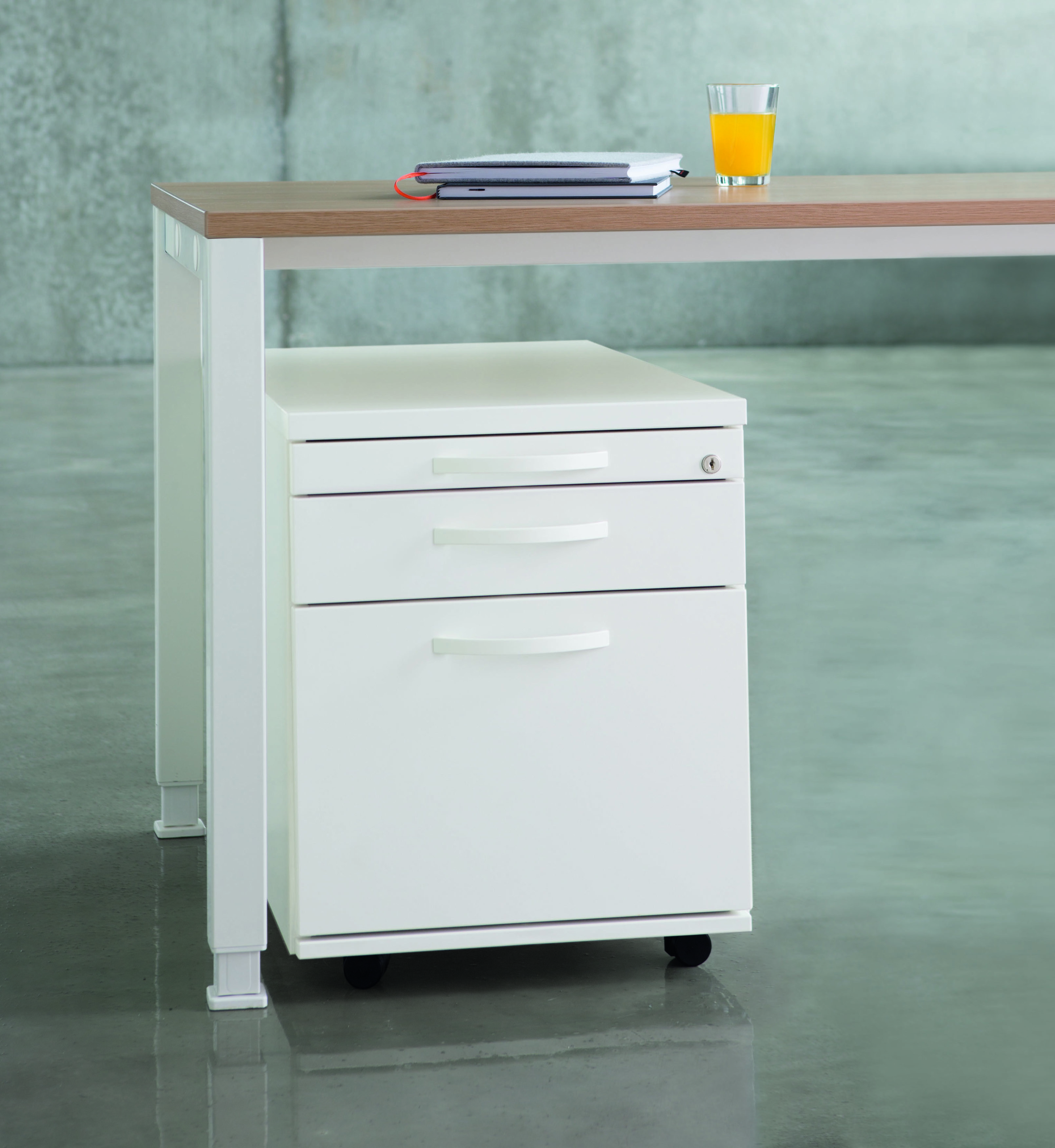 Weißer Rollcontainer von König+Neurath mit drei Schubladen unter einem Schreibtisch, Büromöbel für die Büroorganisation.