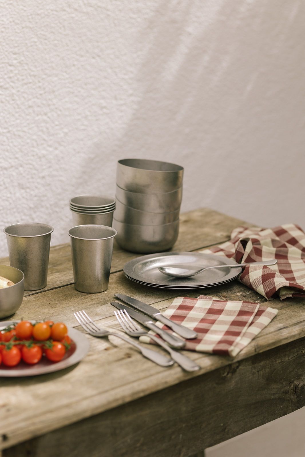 Ferm Living Tumbled Teller und Becher für Picknick oder Camping auf einem Holztisch.