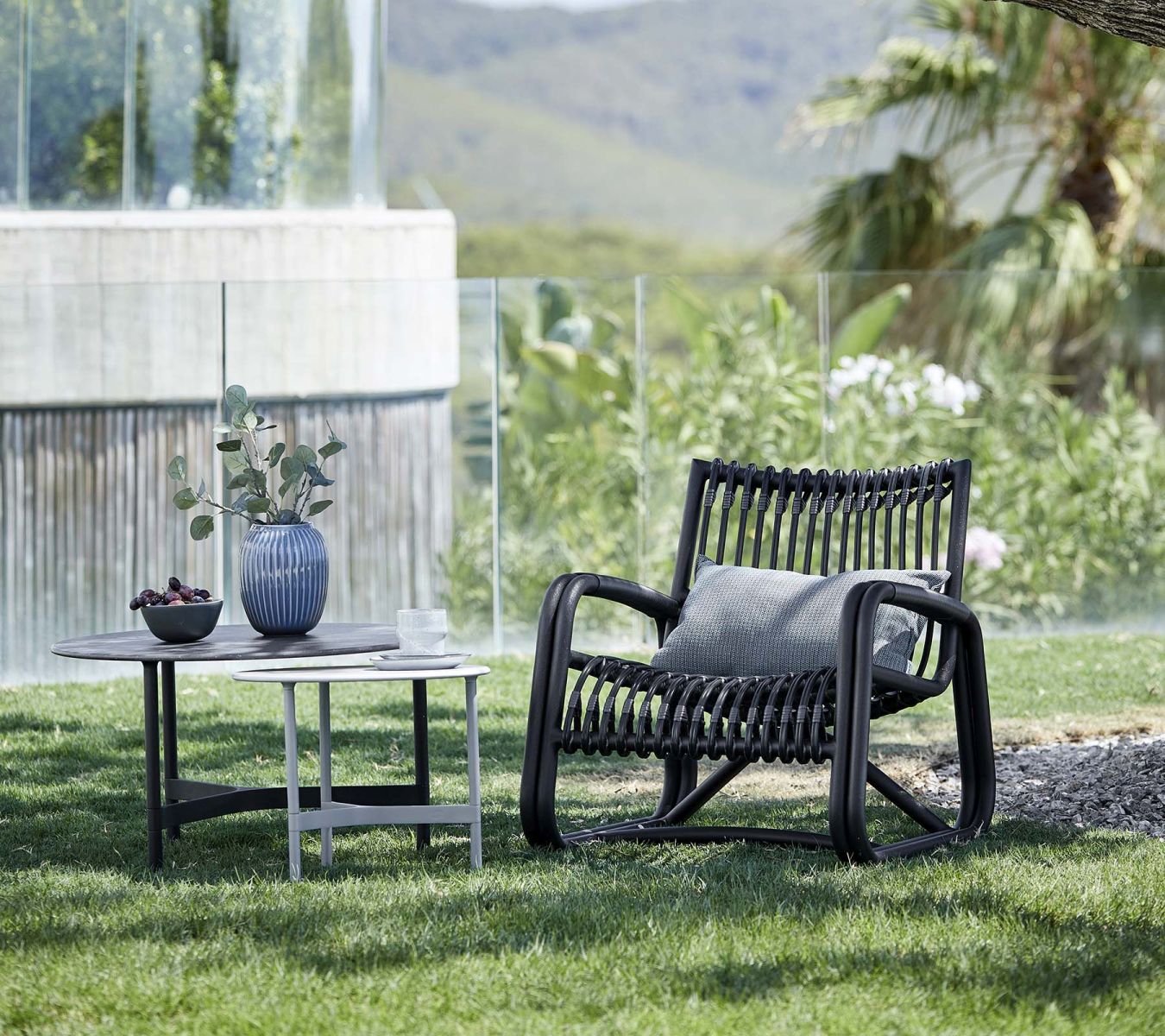 Curve Loungesessel von Cane-Line in Lavagrau mit Kissen im Garten. Outdoor Möbel.