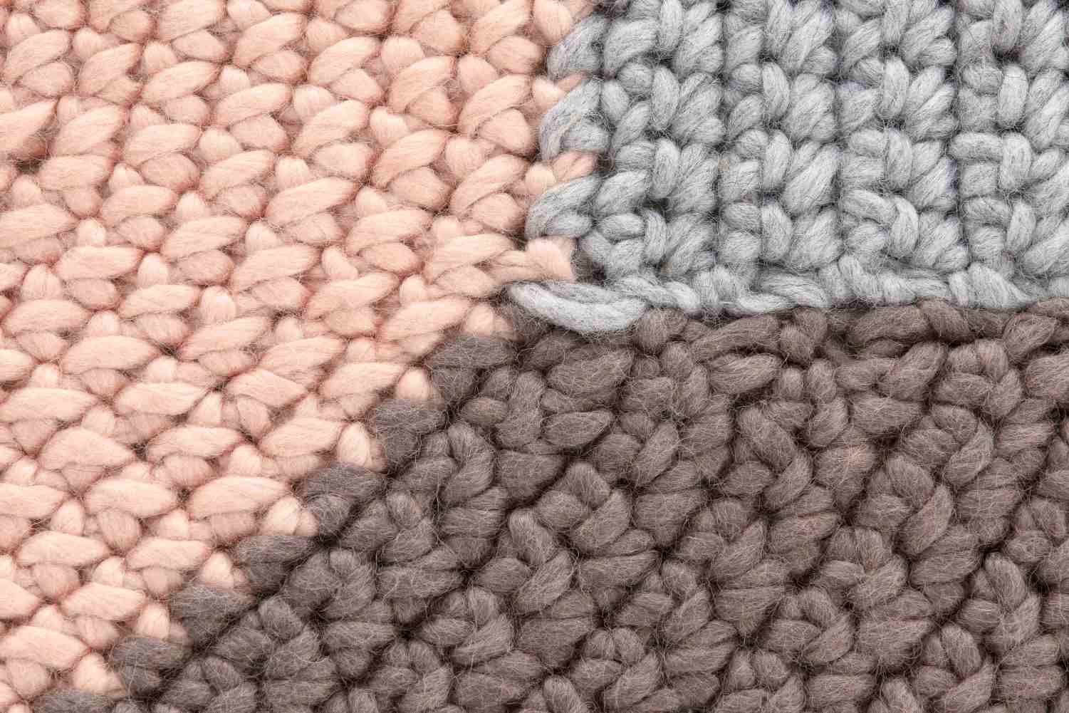 Detailaufnahme des The Crochet Collection Teppichs in Rosa, Grau und Braun, handgefertigter Wollteppich.
