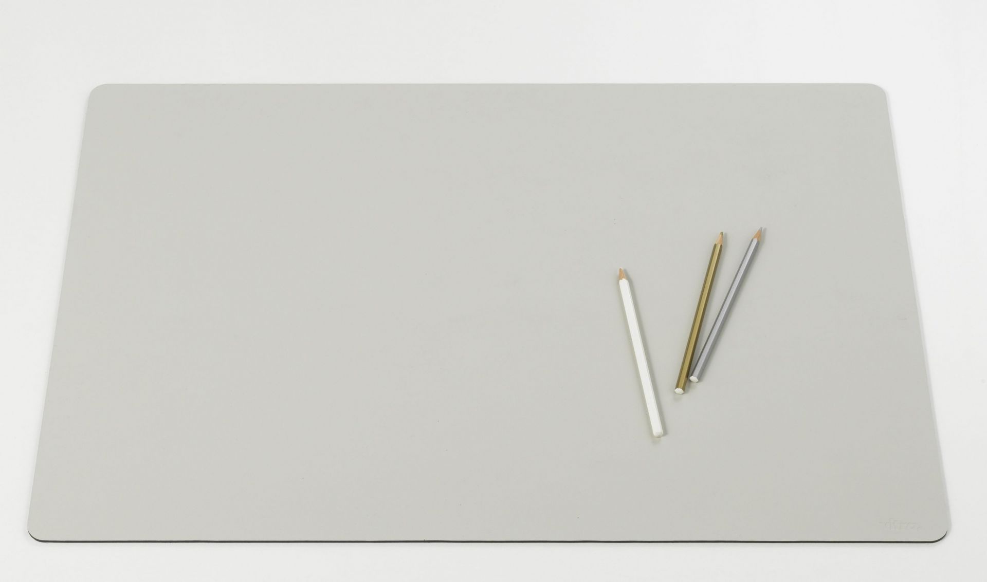 Graue Vitra Schreibtischunterlage Repad auf weißem Hintergrund mit drei Stiften. Büroaccessoire für den Schreibtisch.
