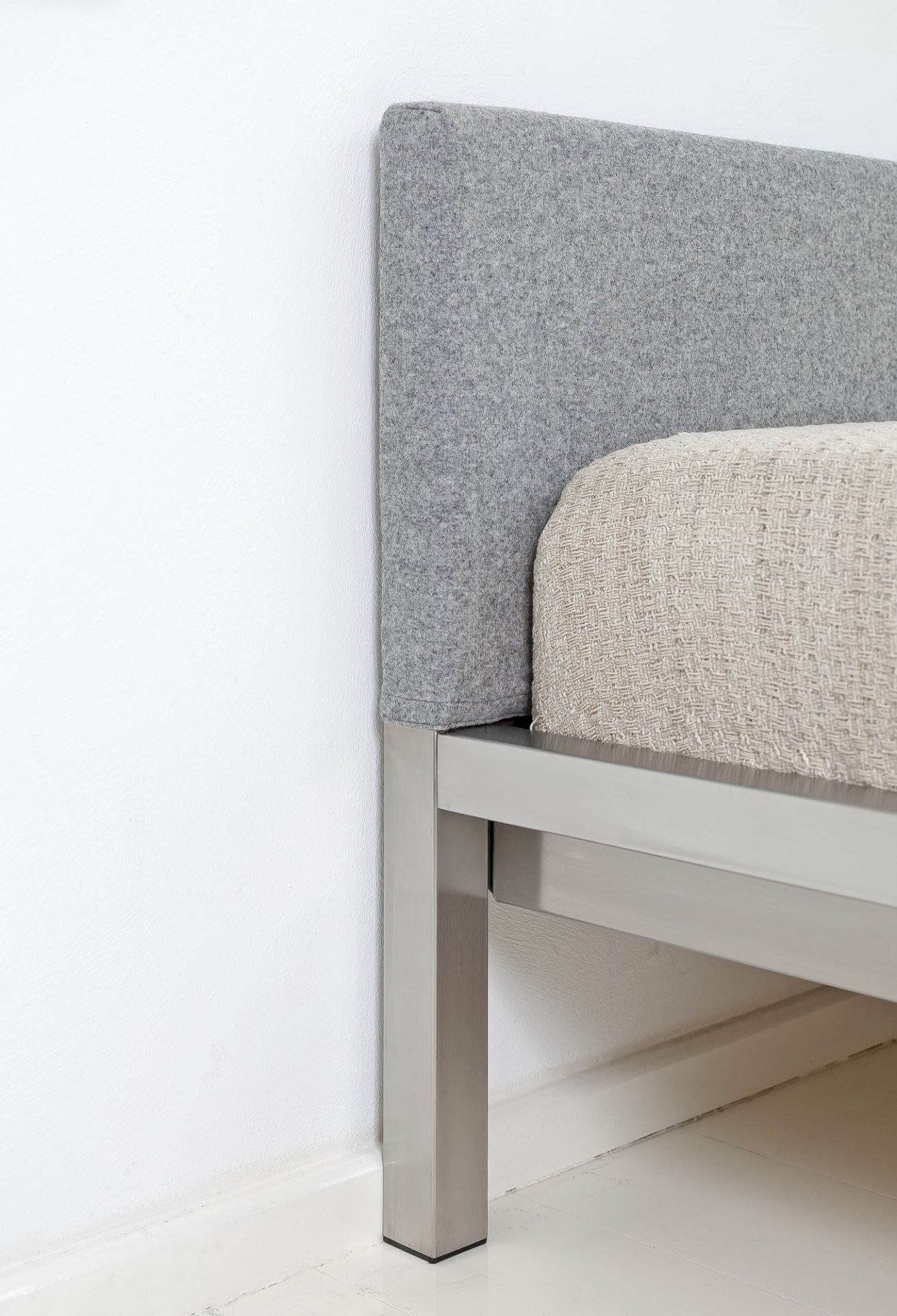 Detailaufnahme: Pure Bett mit Edelstahlrahmen und grauem Velito Polsterkopfteil von Hans Hansen.