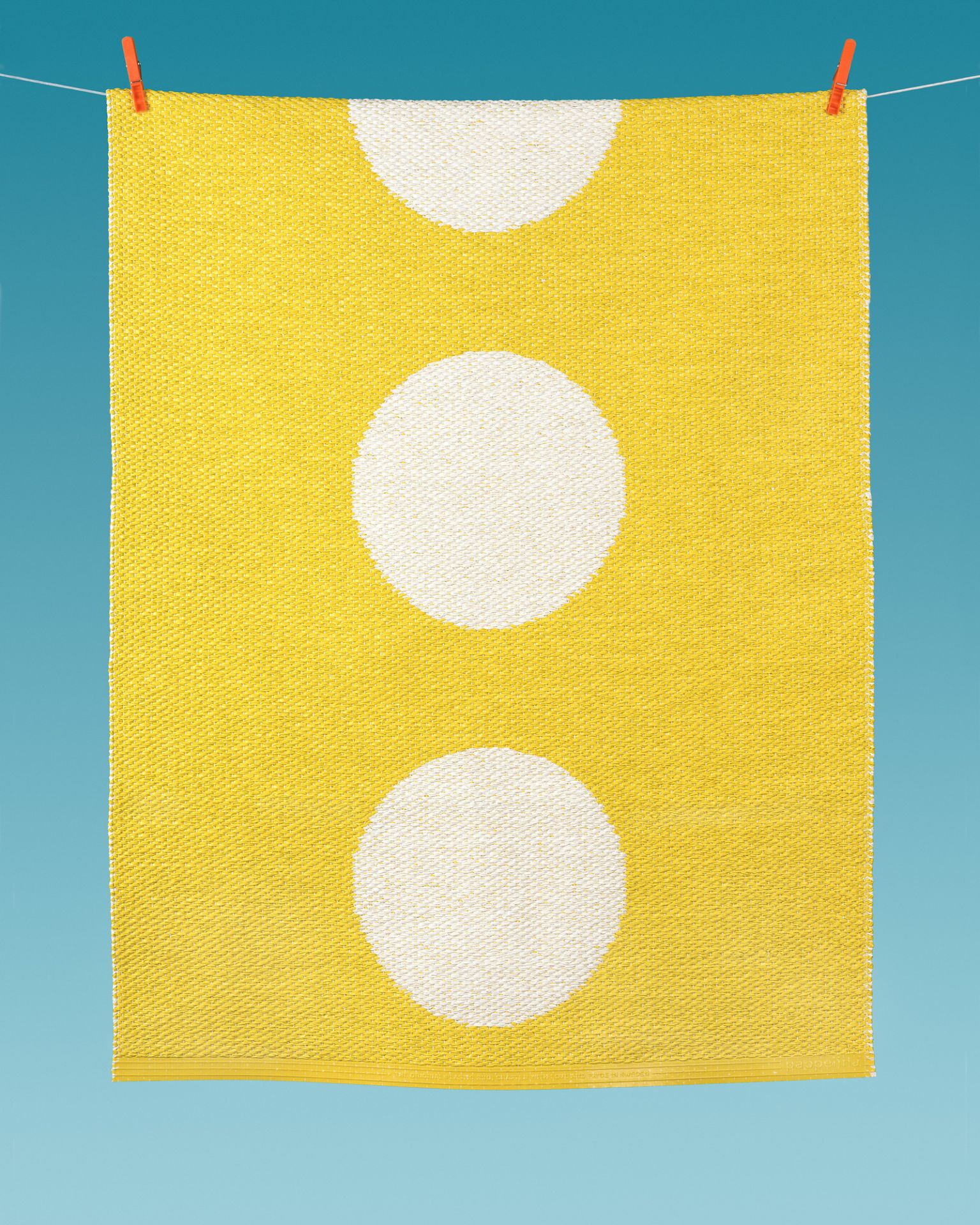 Vera Kunststoffteppich gelb mit weißen Punkten hängt an einer Wäscheleine, ideal für Küche und Bad.