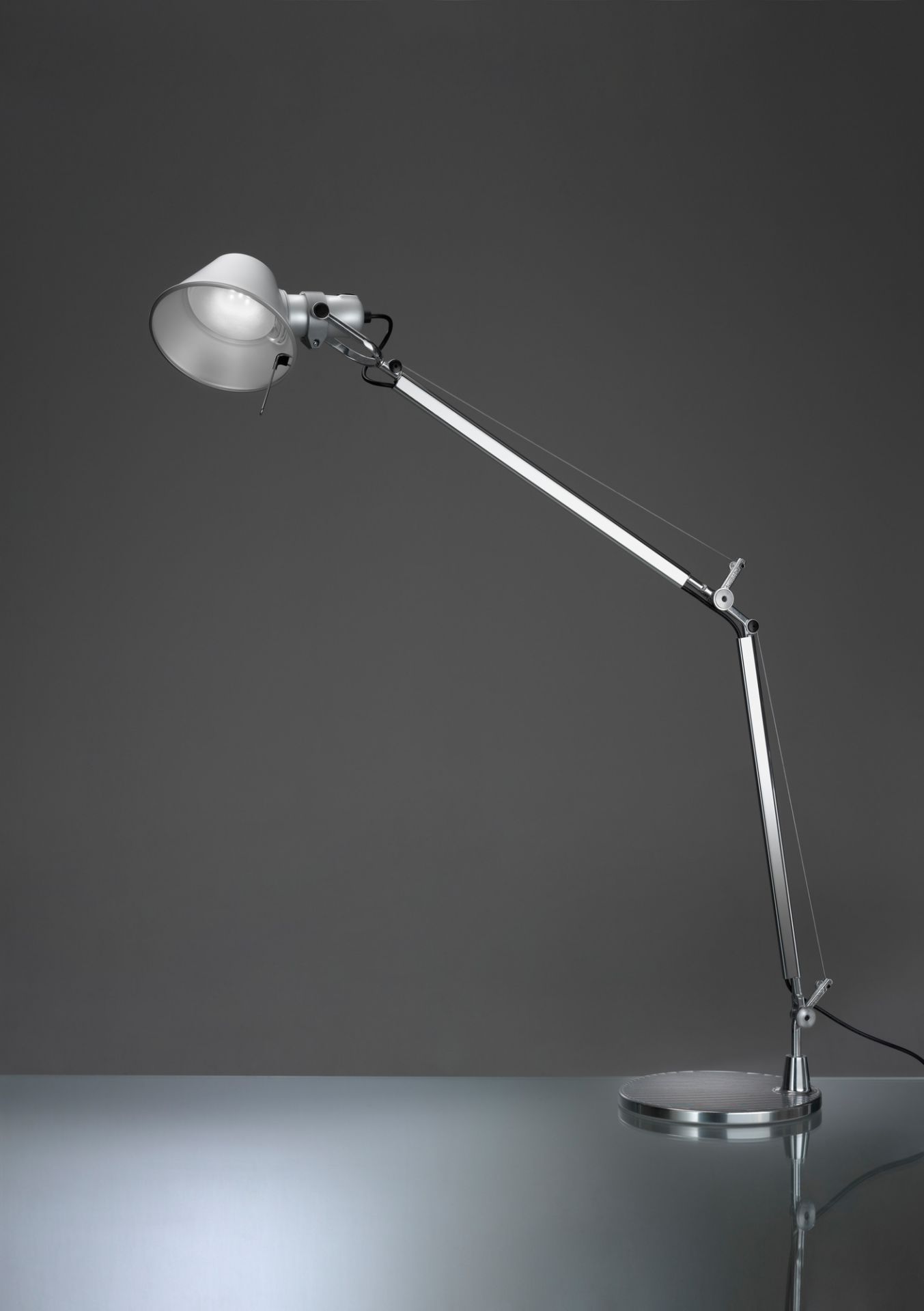 Artemide Tolomeo Tischleuchte mit weißem Lampenschirm und silbernem, verstellbarem Arm auf rundem Tischfuß.