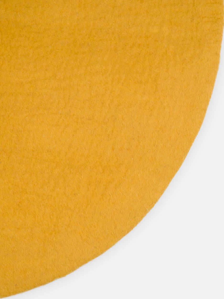 Detailaufnahme: Senfgelber, runder Filzteppich von myfelt, Modell Klara, Textur und Farbe im Fokus.