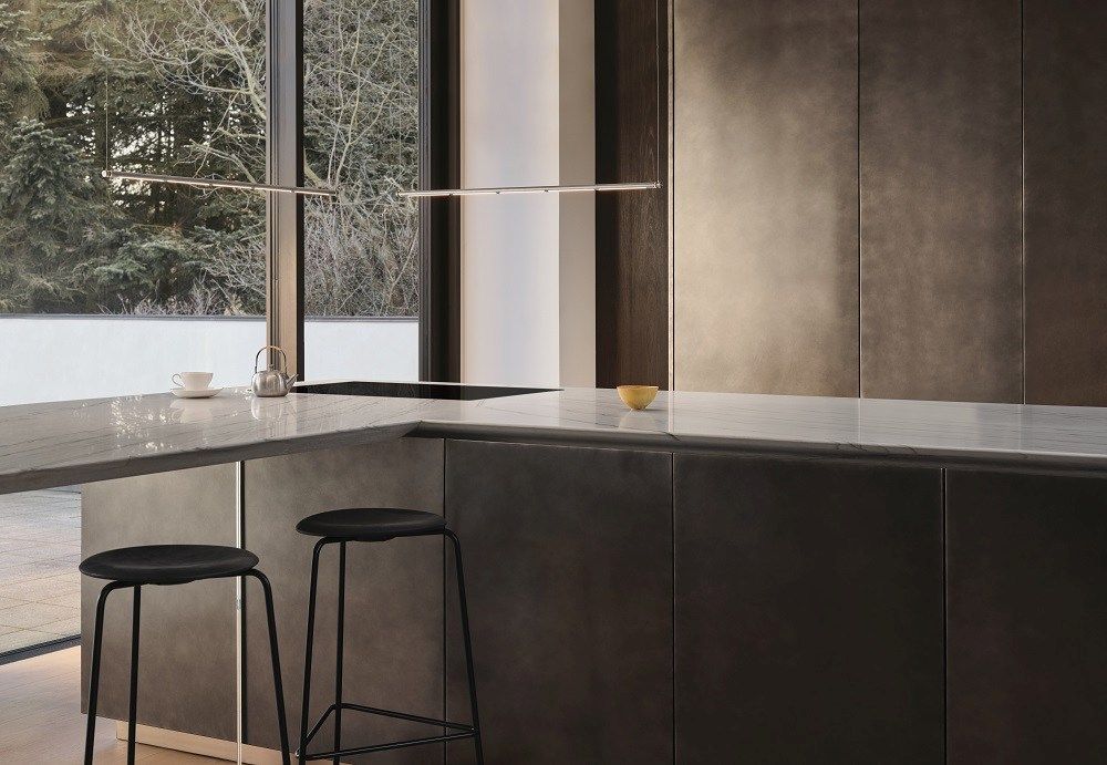 Oneline Pendelleuchte von Fritz Hansen über einer modernen Kücheninsel mit Barhockern und Marmorarbeitsplatte.