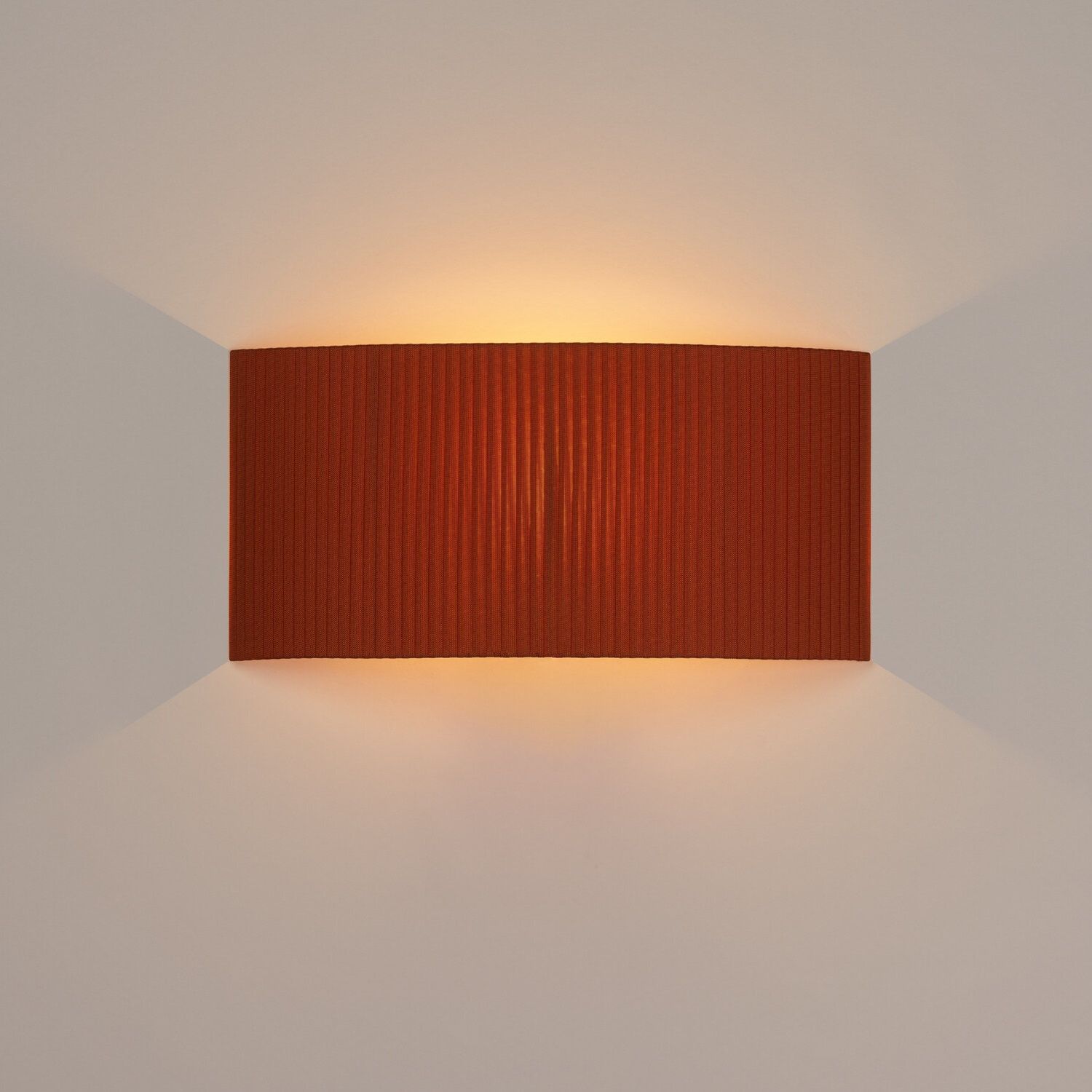 Rechteckige Wandleuchte Comodín in Terrakotta mit gerippter Textur und warmem Lichtschein.