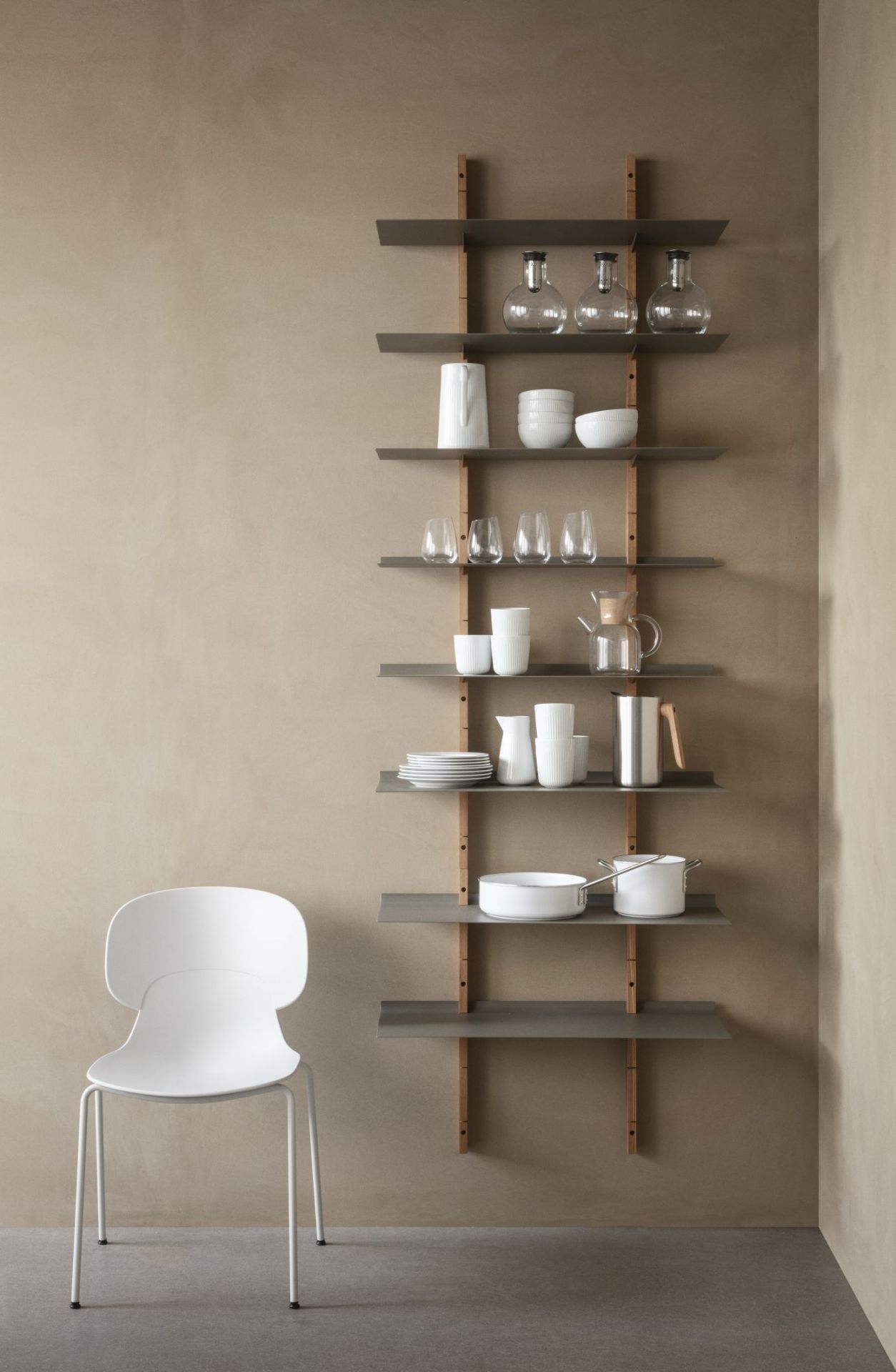 Combo Stuhl - weiß - ungepolstert Eva Solo Weißer Combo Stuhl von Eva Solo, ungepolstert, mit minimalistischem Design und Metallbeinen vor Regalwand.
