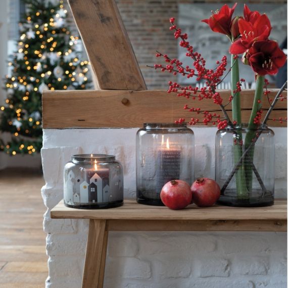 Wintervase Häuser Winterlicht Räder Winterliche Dekoration mit Räder Winterlicht Häuser Windlicht, roten Blumen und Granatäpfeln auf Holzbank.