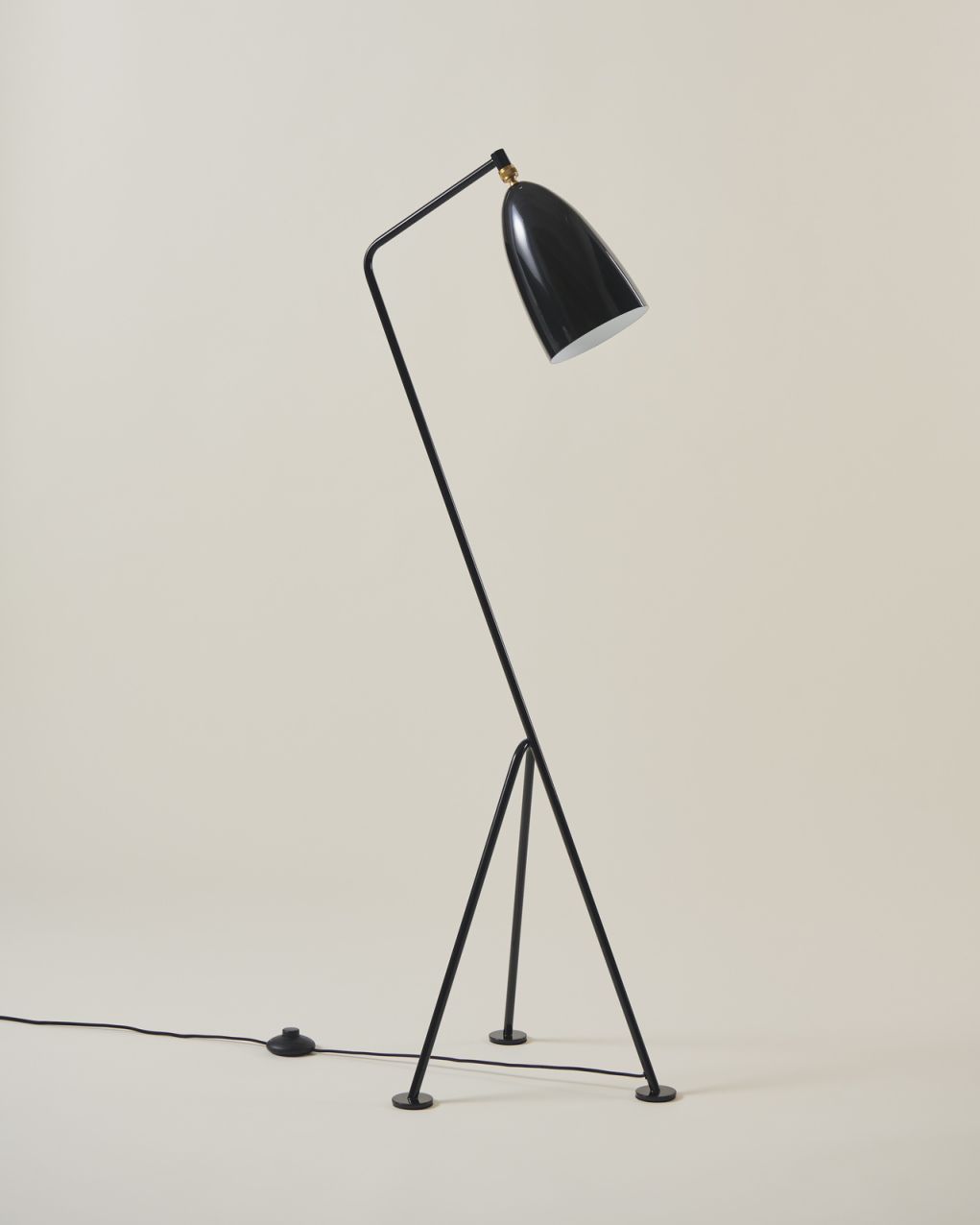 Schwarze Gräshoppa Stehleuchte von Gubi mit glänzendem Lampenschirm und filigranem, dreibeinigem Gestell.