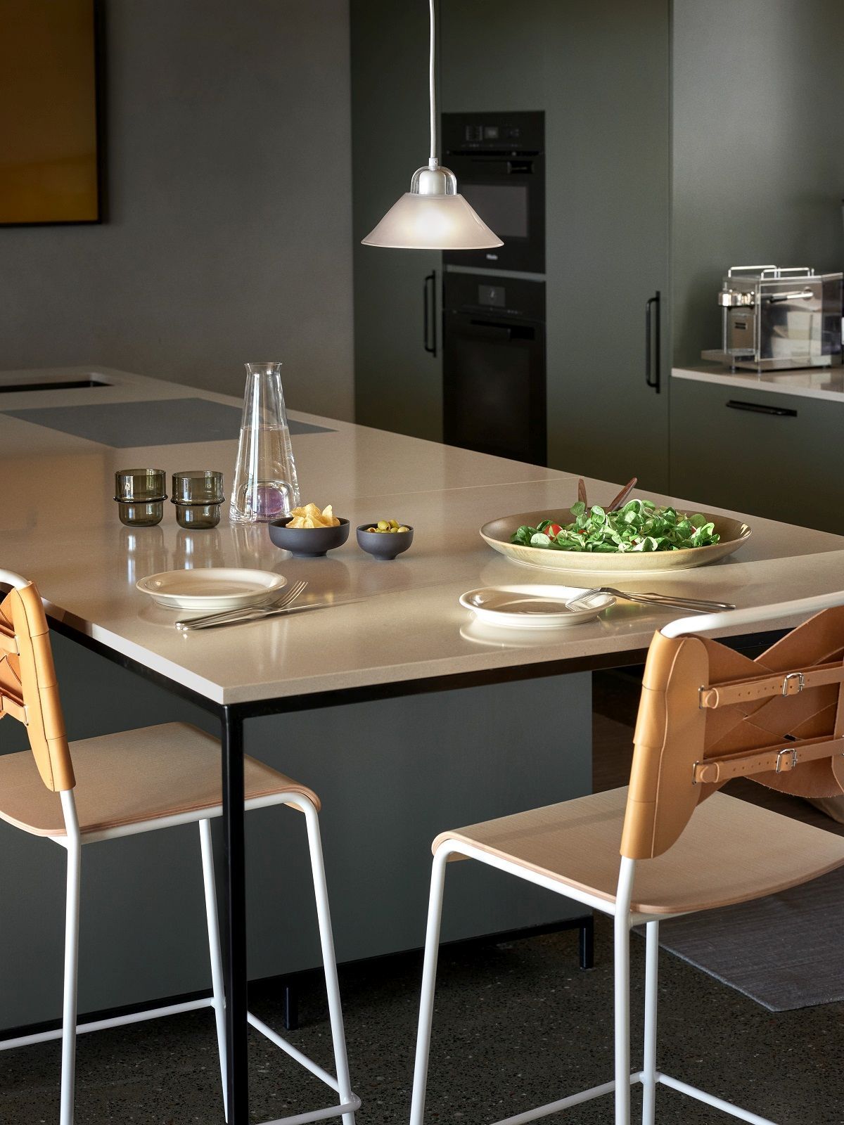 Kalo Lamp Pendelleuchte von Design House Stockholm über Esstisch mit Geschirr und Stühlen.