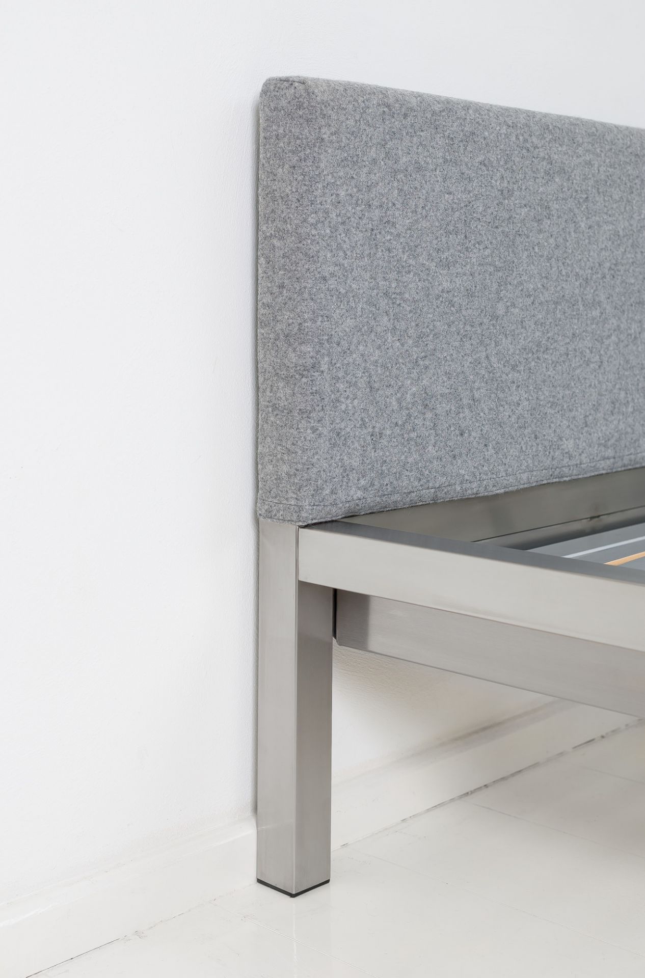 Detailaufnahme: Pure Bett mit Edelstahlrahmen und grauem Velito Polsterkopfteil von Hans Hansen.