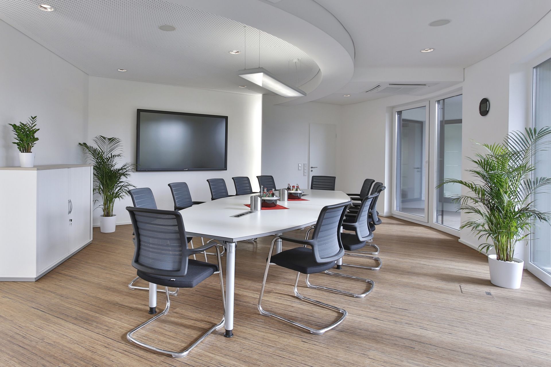 Heller Besprechungsraum mit Systo Tec Konferenztisch von Palmberg, Bürostühlen und großem Bildschirm für Präsentationen.