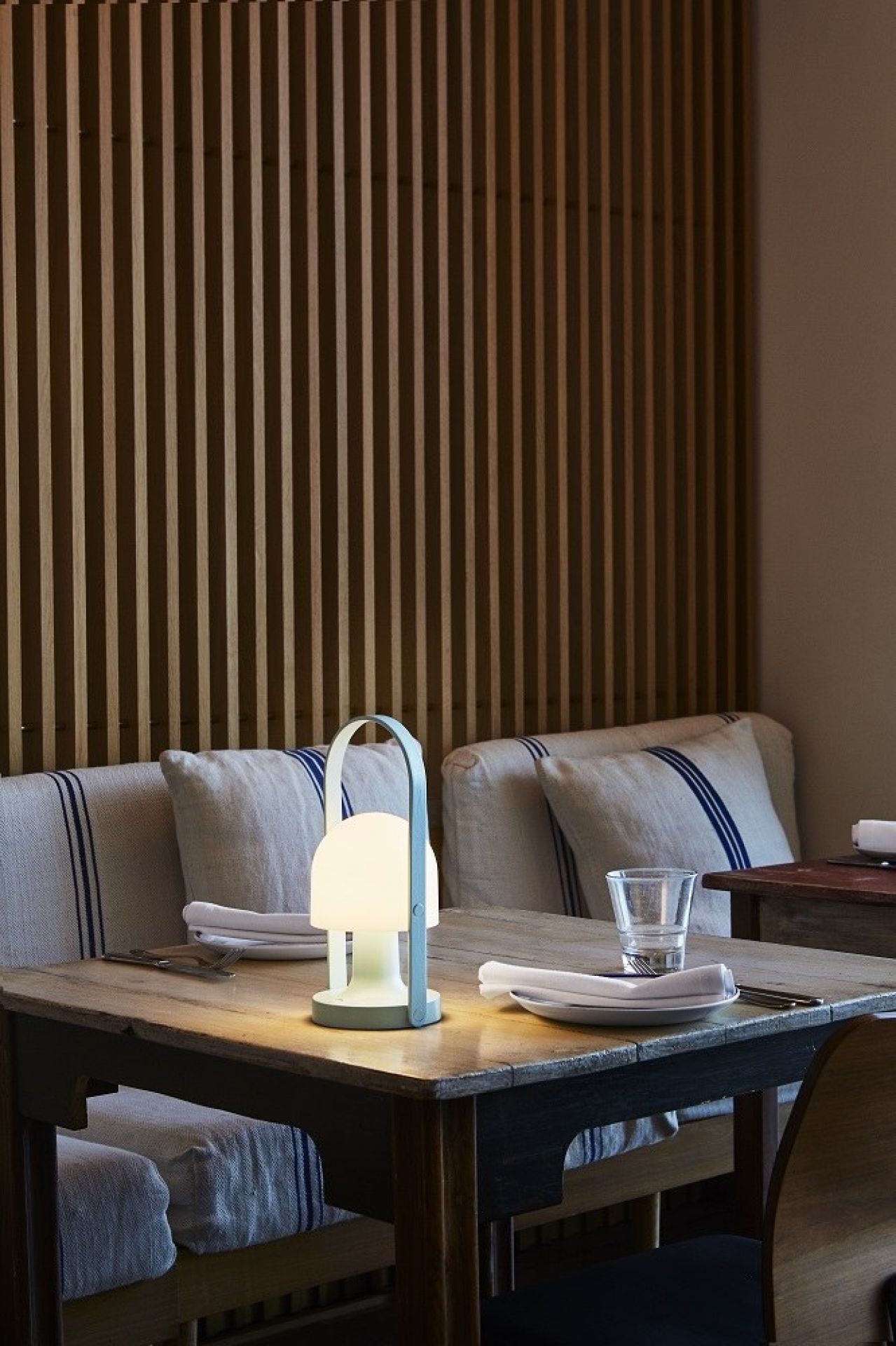 FollowMe LED Akkuleuchte von Marset auf gedecktem Tisch im Restaurant, warmes Licht.