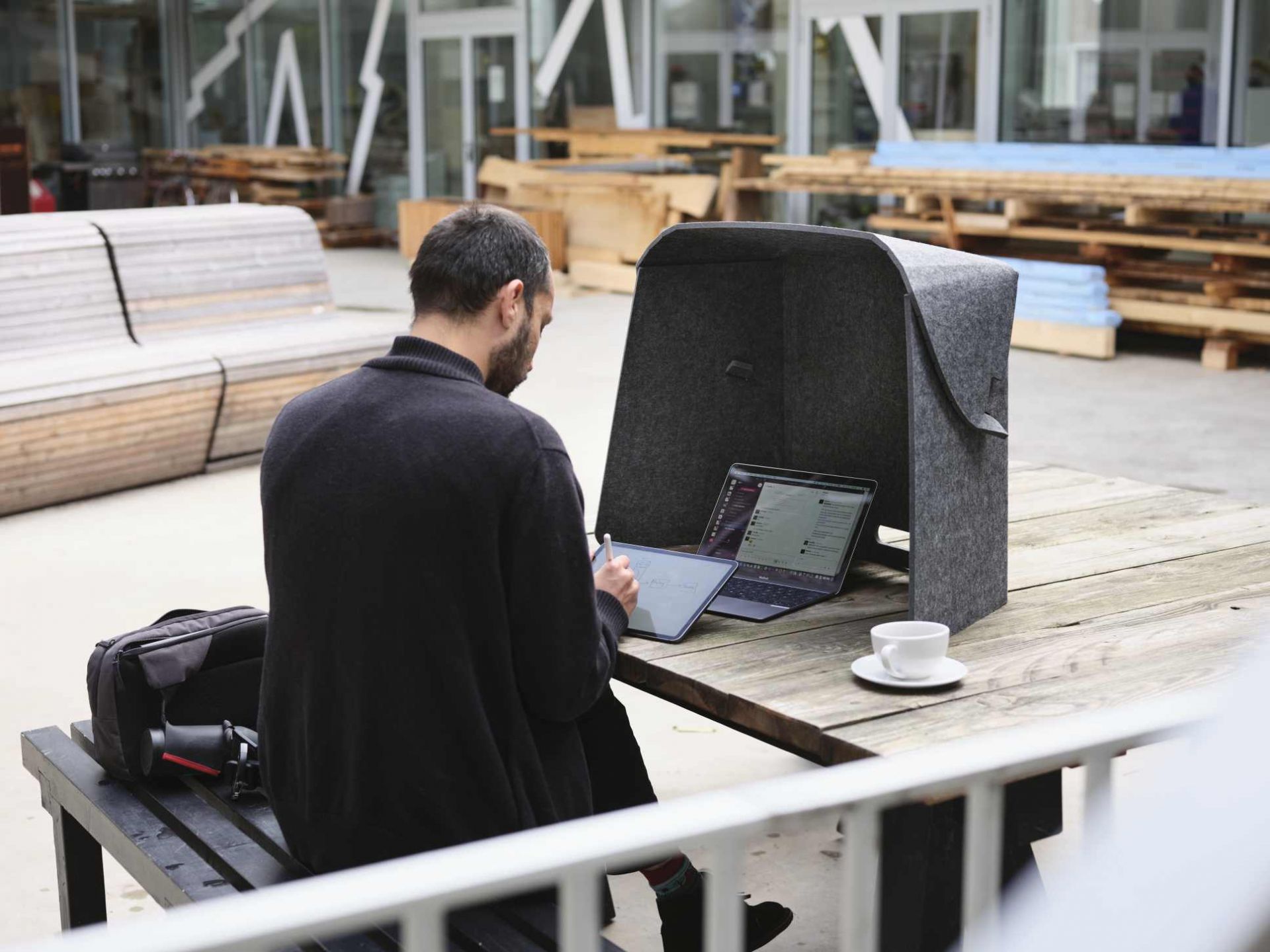 Fold-Up-Workspace Wilkhahn Mann arbeitet mit Laptop und Tablet im Fold-Up-Workspace von Wilkhahn im Freien.