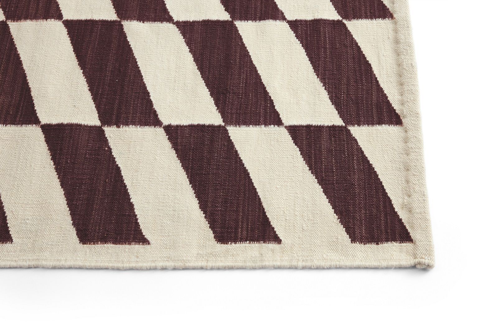 Detailaufnahme des Shift Kelim Teppichs von Hay mit geometrischem Muster in Beige und Burgunderrot.