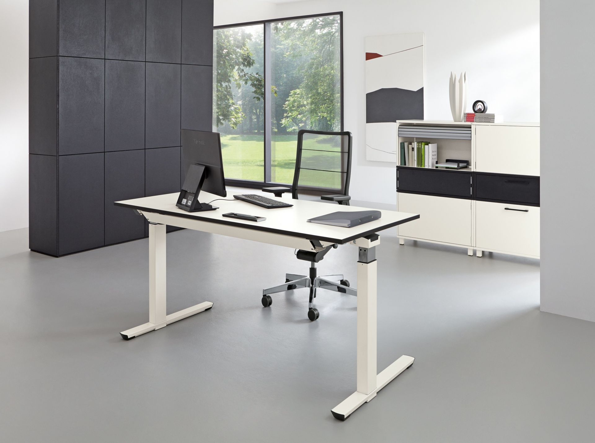 Moderner, höhenverstellbarer Palmberg Schreibtisch mit Bürostuhl, Monitor und Büromaterial in einem hellen Büro.