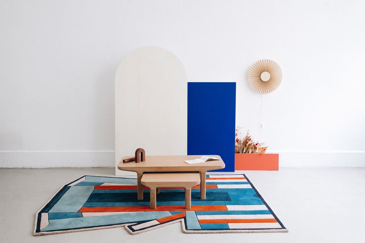 Inès Teppich von Hartô mit geometrischem Muster in Grau, Blau und Orange im Raum.