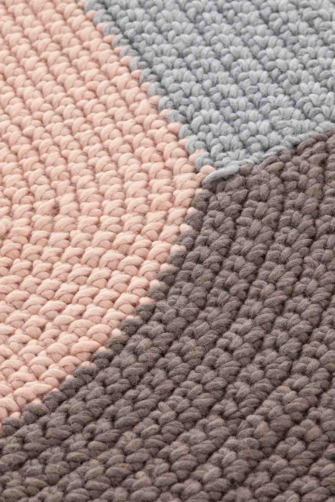 Detailaufnahme des The Crochet Collection Teppichs in Rosa, Grau und Braun mit auffälliger Häkelstruktur.